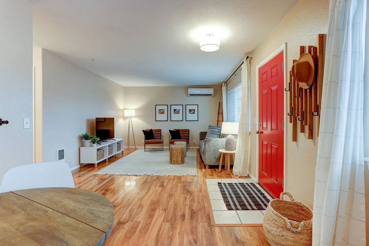 A welcoming entryway with a bold red door, a comfortable seating area, decorative art frames, and a cozy area rug. This space is designed for guests to easily transition from outdoors to indoors while stowing shoes or gear.