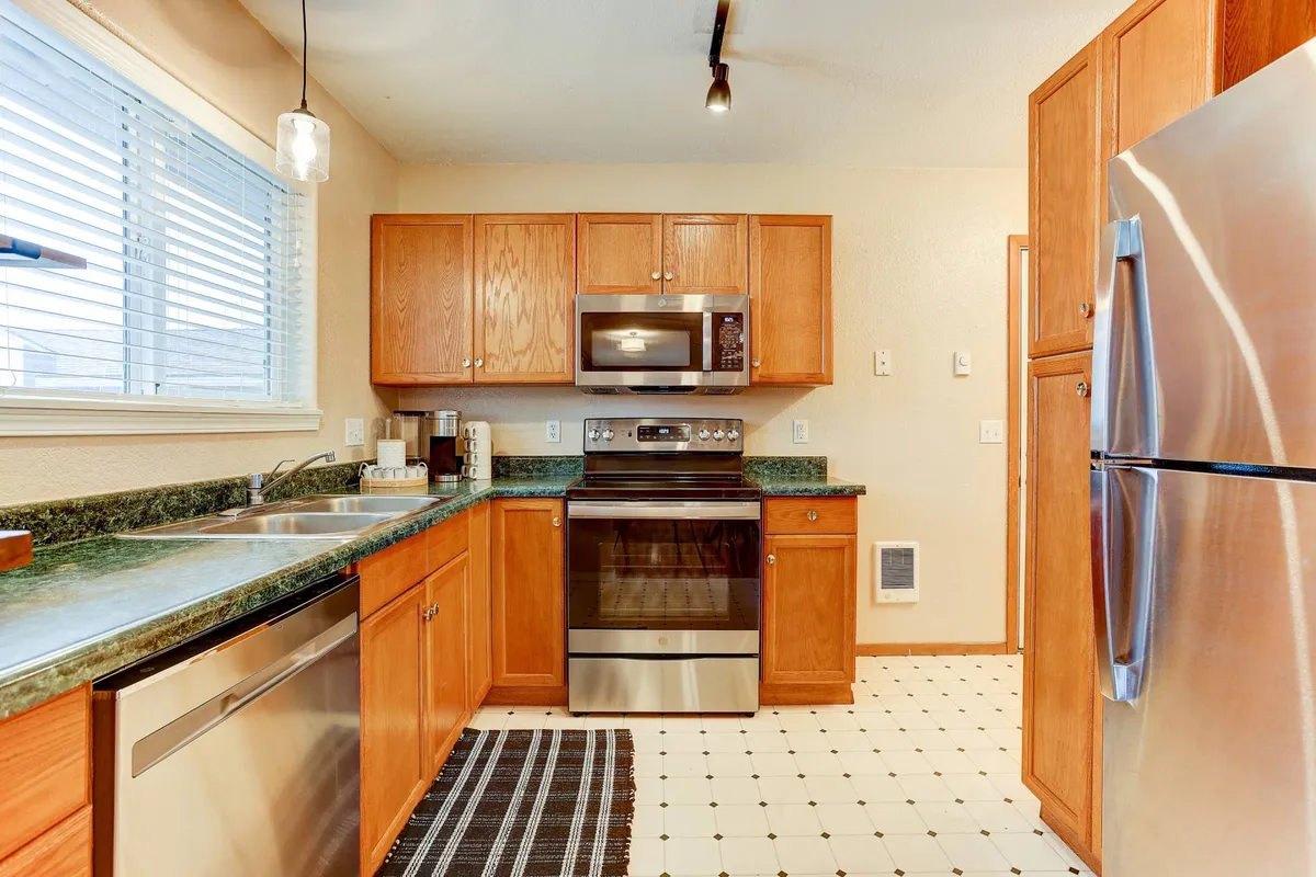 A modern kitchen with stainless steel appliances, granite countertops, and wood cabinetry centered around a versatile kitchen island. The setting feels warm and welcoming, ideal for cooking, entertaining, and gathering over meals.